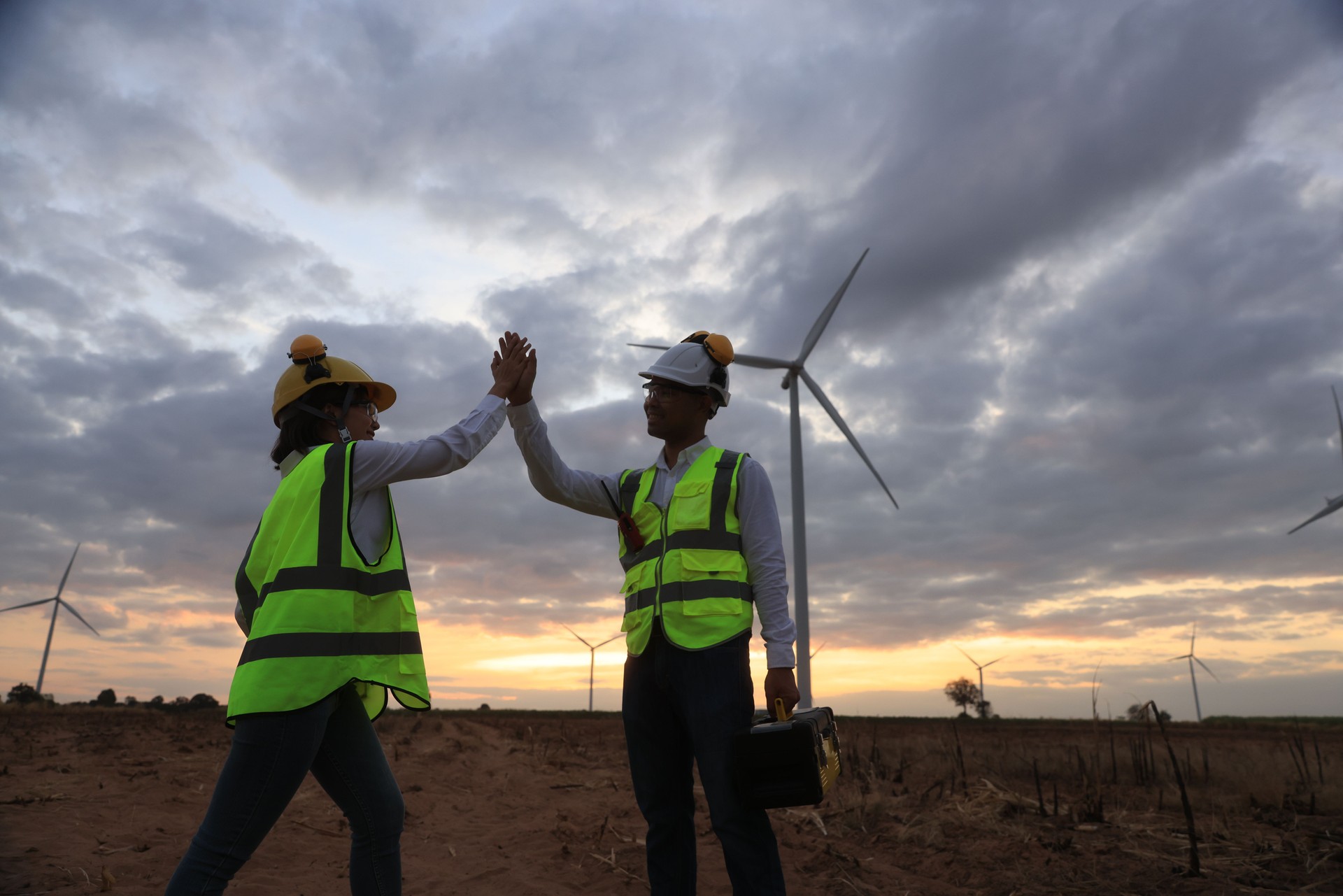 Colega ingeniero toque la mano para la expresión exitosa del trabajo después de terminar el trabajo en el campo de turbinas eólicas